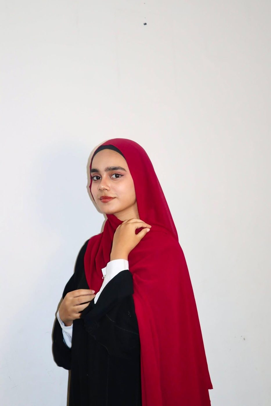 Arfa in a red hijab, looking over her shoulder