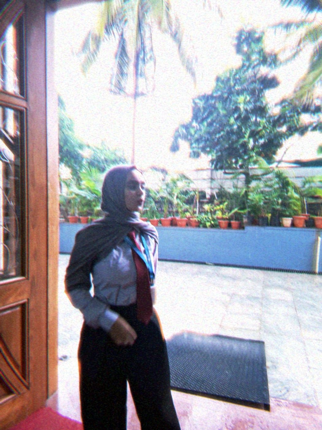 Arfa standing at a doorway with palm trees behind