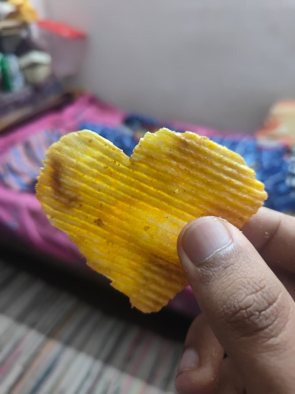 A heart shaped potato chip held between fingers